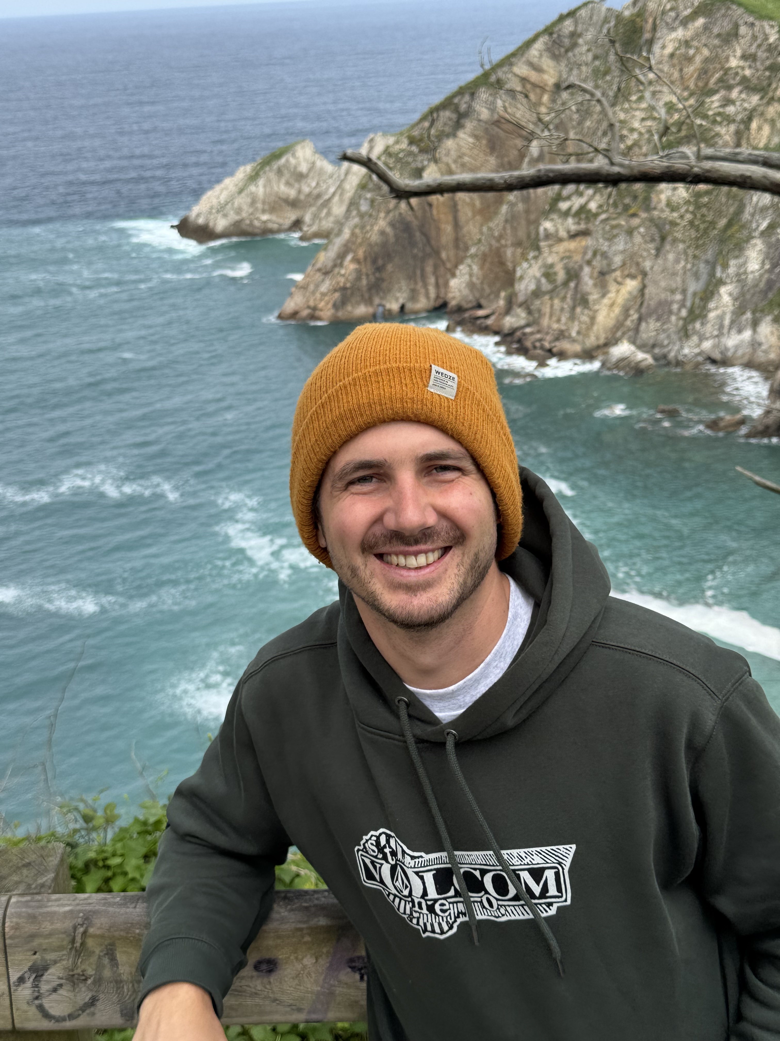 Photo of Thomas smiling by the ocean